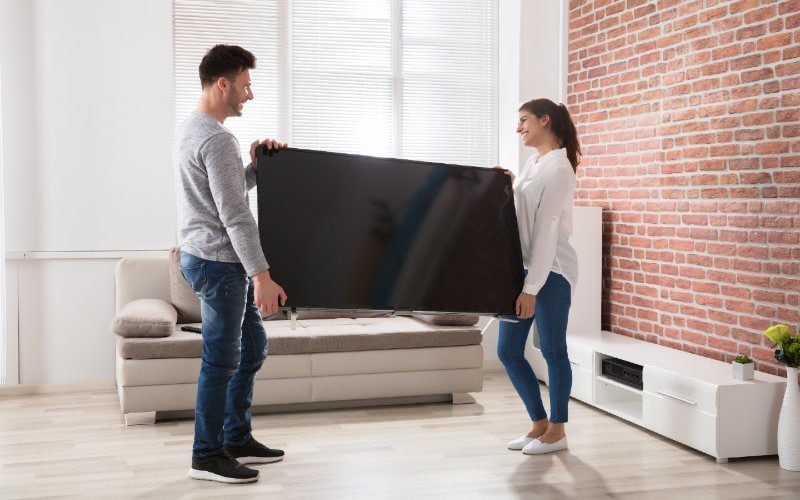 two people carrying a television