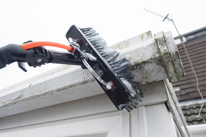 using a brush to clean gutter