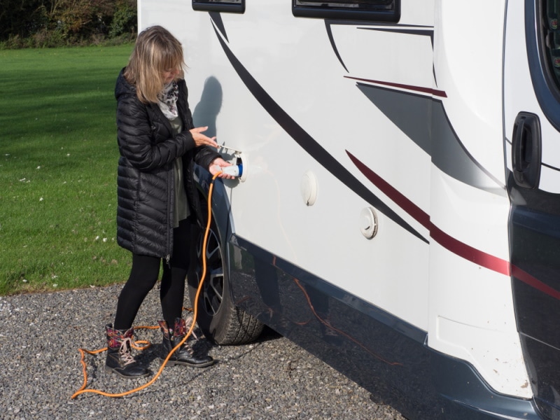 woman plugging in power supply to her RV