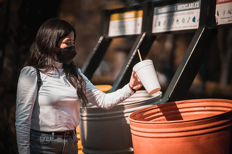 woman throwing styrofoam cup on the bin