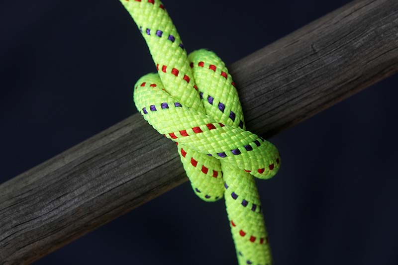Bright green nylon rope tied around old wooden pole, clove hitch