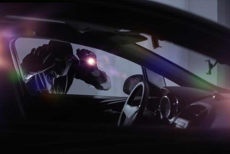 Car Robber with Flashlight Looking Inside the Car
