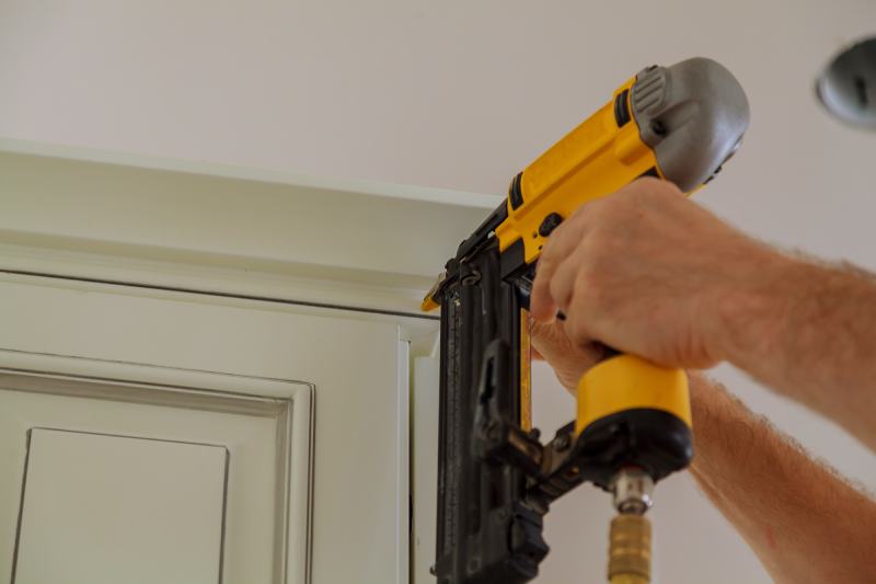 Carpenter brad using nail gun to Crown Moulding (Electric Framing Nailers)