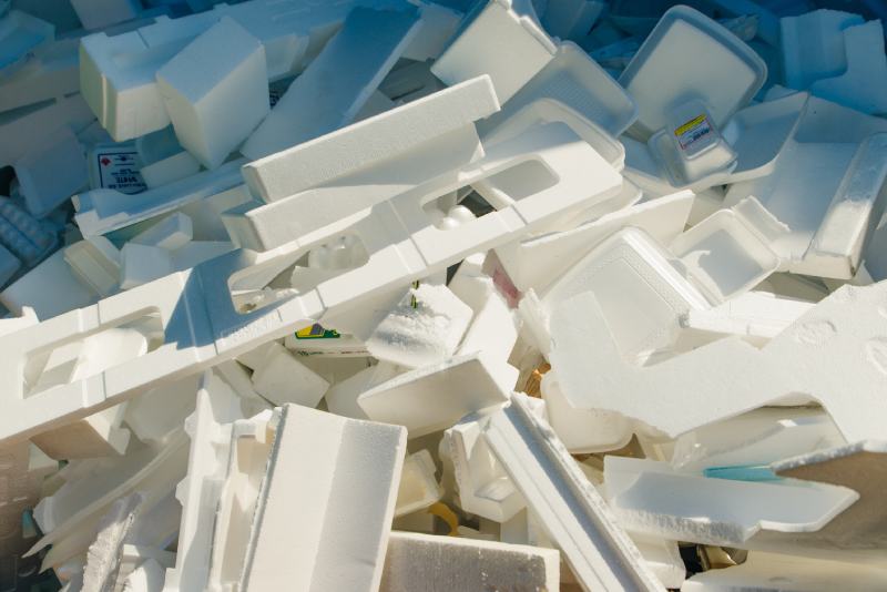 Close up white isolated photo of used foam thermocol plates with food stains heaped at a garbage