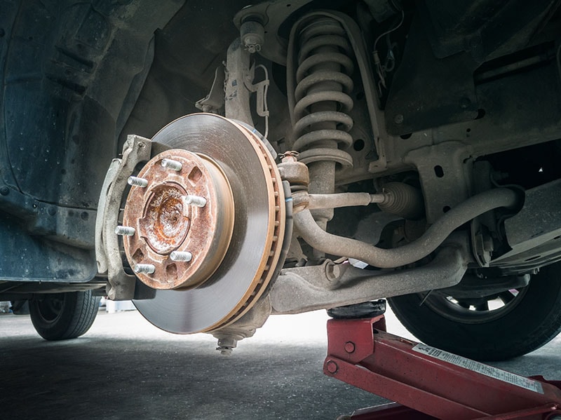 Closeup view of a truck's front disc brake with visible suspension system.