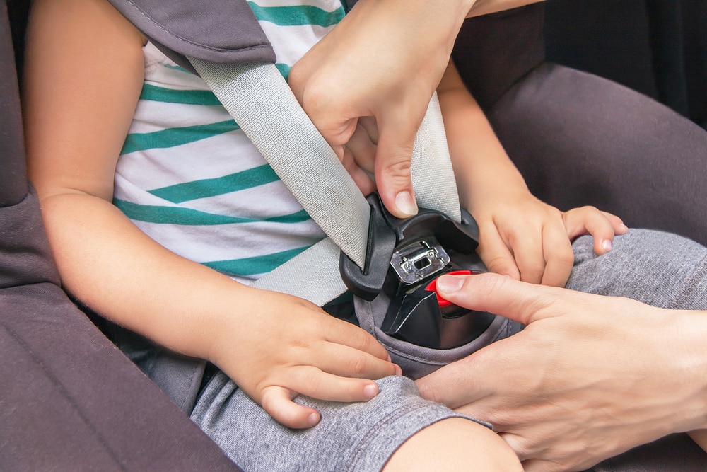 Hands of caucasian woman is fastening security belt to child