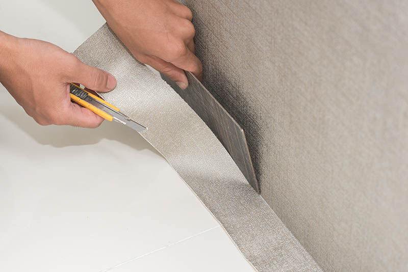 Handyman putting up wallpaper on the wall with a scraper