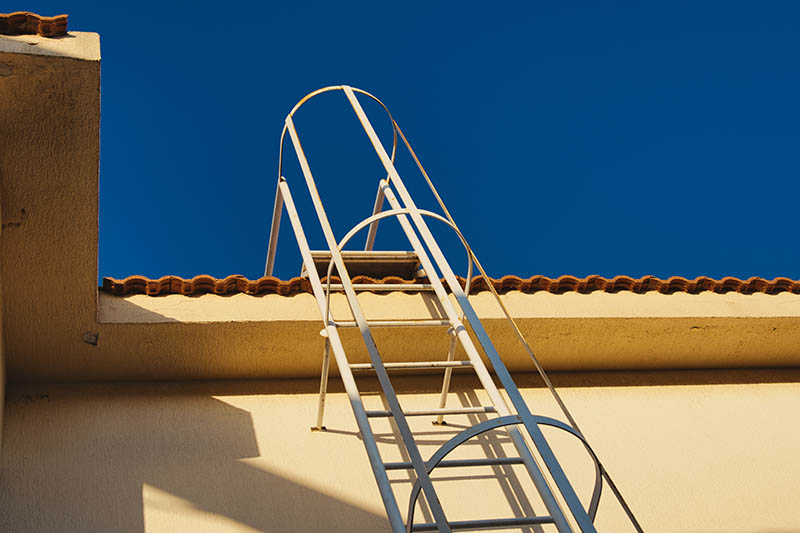 Outdoor metal stairs to the roof of the house. Fire escape access to the tiled roof