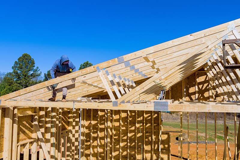 Standard timber framed building with close up on the roof trusses workers nailing wood beams