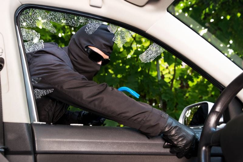Thief successfully breaking a car's window try to steal it