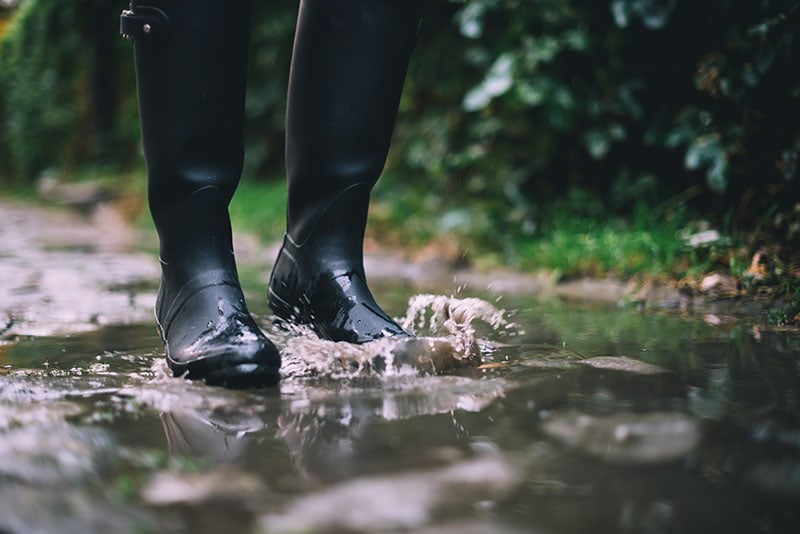 Woman in black rubber boots standing in a puddle
