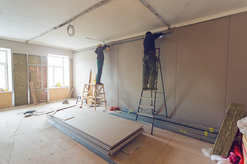Workers are installing plasterboard (drywall) for gypsum walls in apartment is under construction