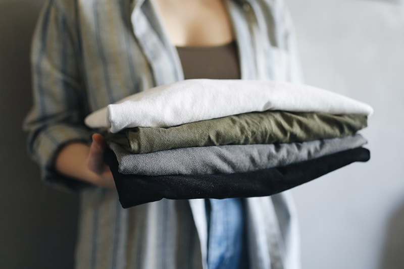 a person holding a stack of neatly folded shirts