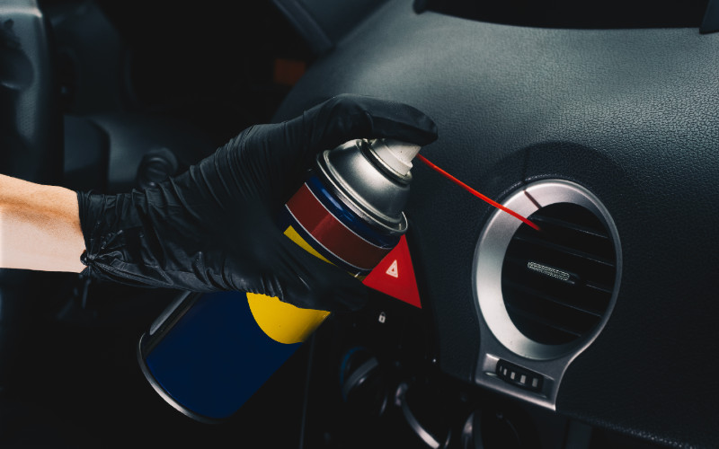 a person spraying lubricant to clean car vent