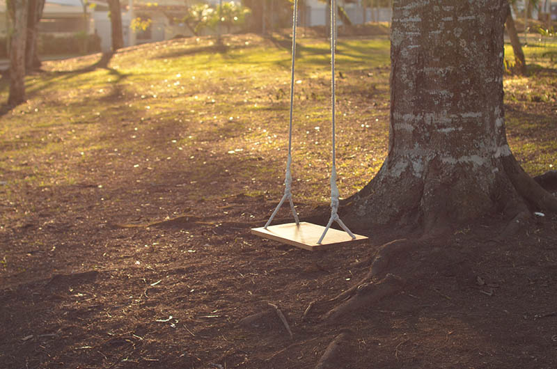 a wooden swing hanging on a tree