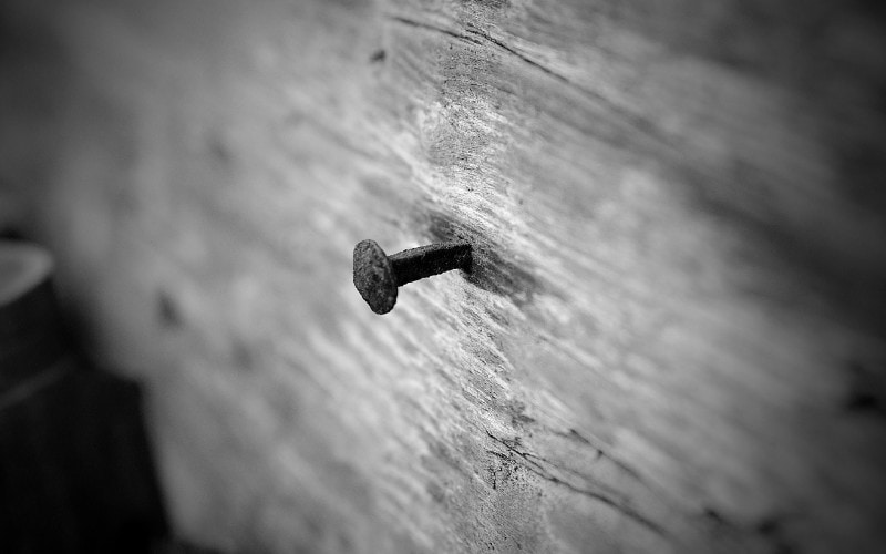 black and white photo of nail sticking out from the wall
