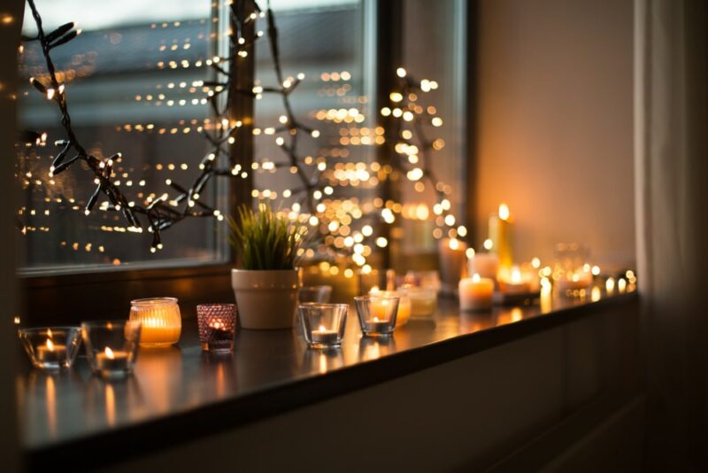 candles burning in lanterns on window sill