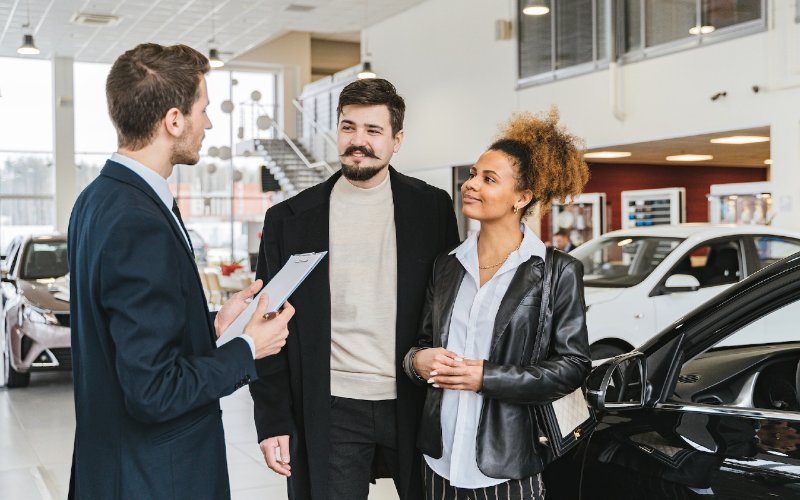 car salesman talking to a couple at the dealership