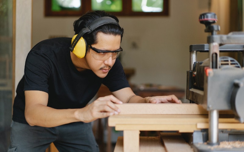 carpenter using a planer in woodworking