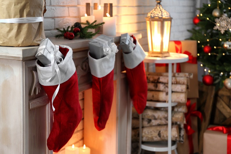 christmas stockings with gifts on decorative fireplace