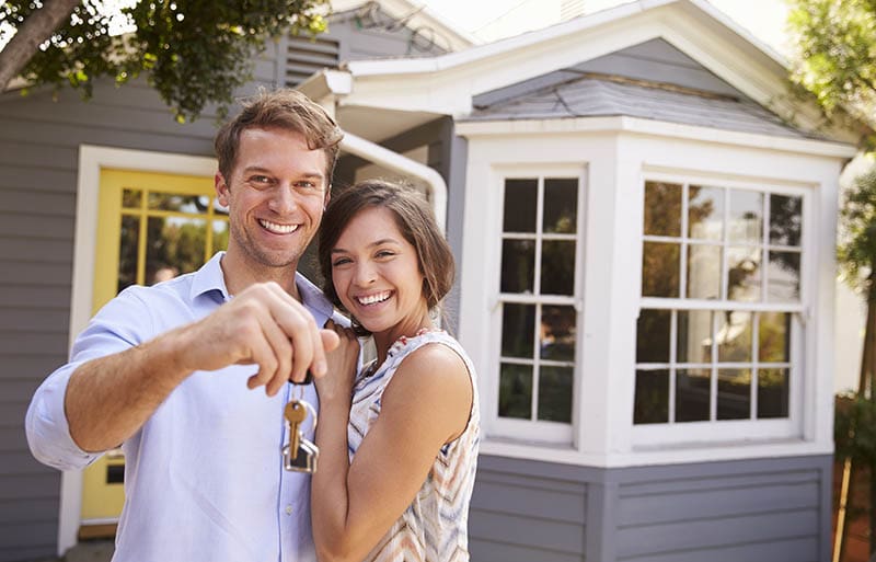 couple with keys outside a home