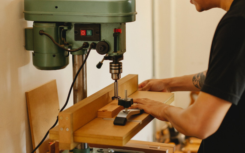 craftsman drilling hole into wood with a drill press