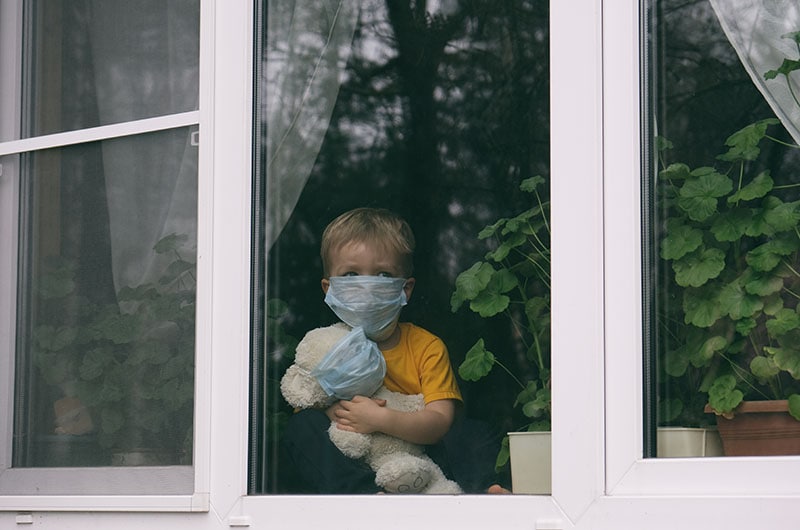 kid wearing mask inside his home during the pandemic