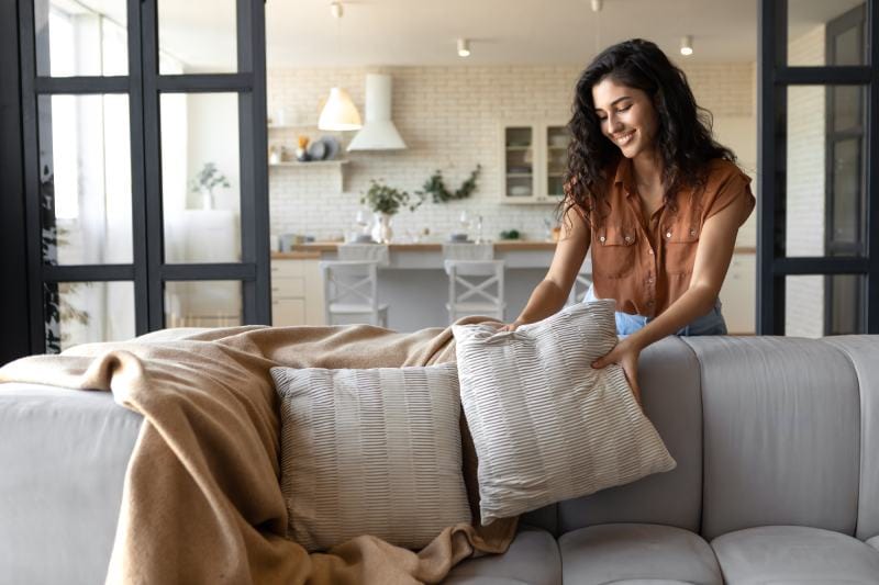 lady decorating her couch with cushions and blanket