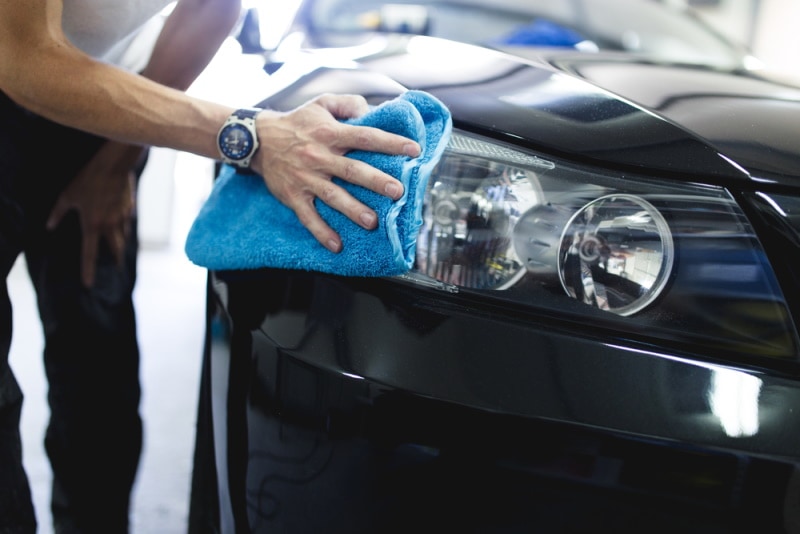 man cleaning car headlight