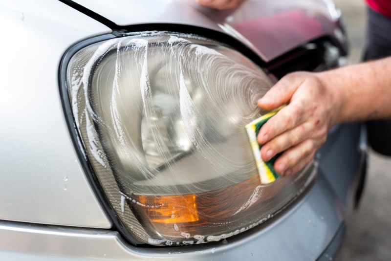man cleaning headlight