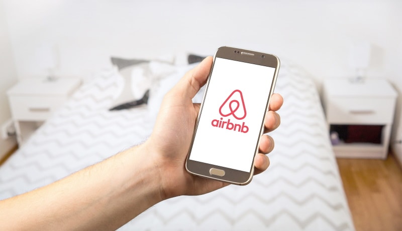 man holding smartphone with airbnb logo
