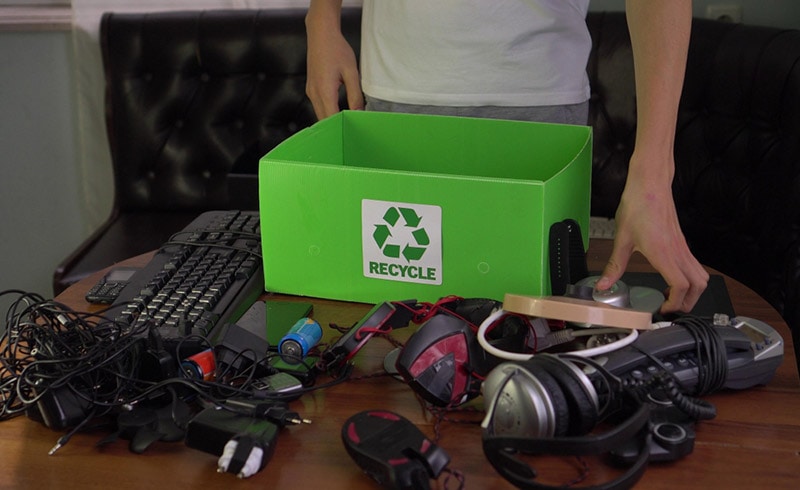 man putting old electronics in a recycling container