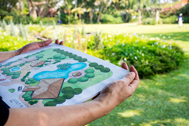 paper sheet of layout plan with hands and garden background