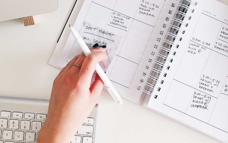 person creating a schedule with a notebook planner