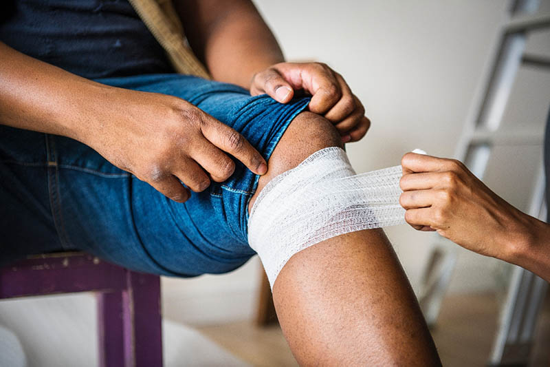 putting bandage on person's injured leg