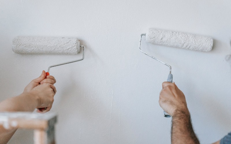two people painting a wall white