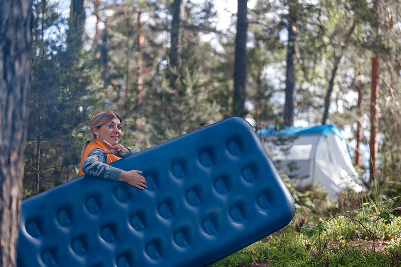 woman carrying air mattress in the woods