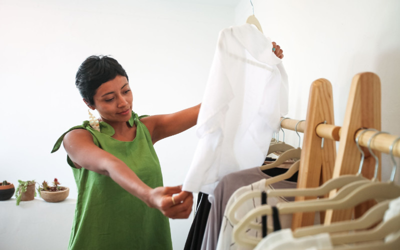 woman picking through clothes on velvet hangers