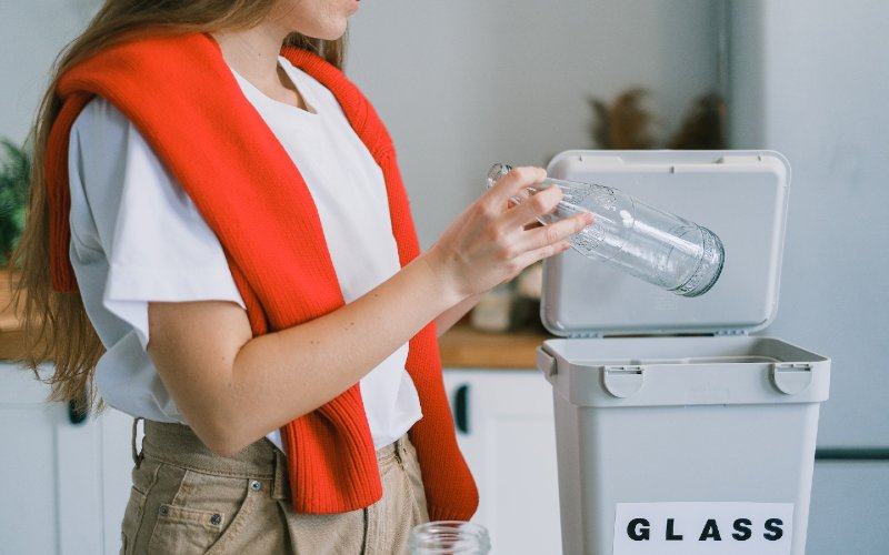 woman putting used bottle into recycling bin