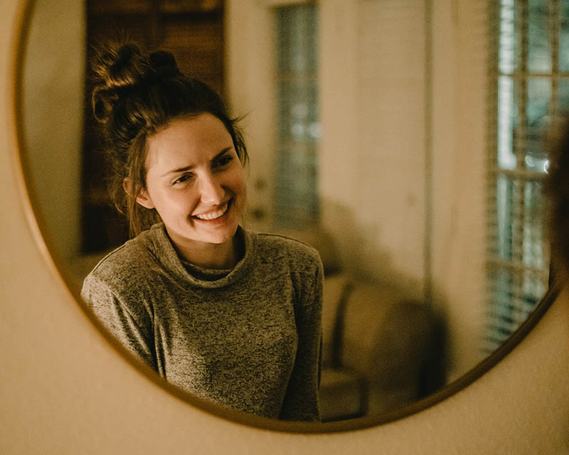 young woman smiling to herself on the mirror