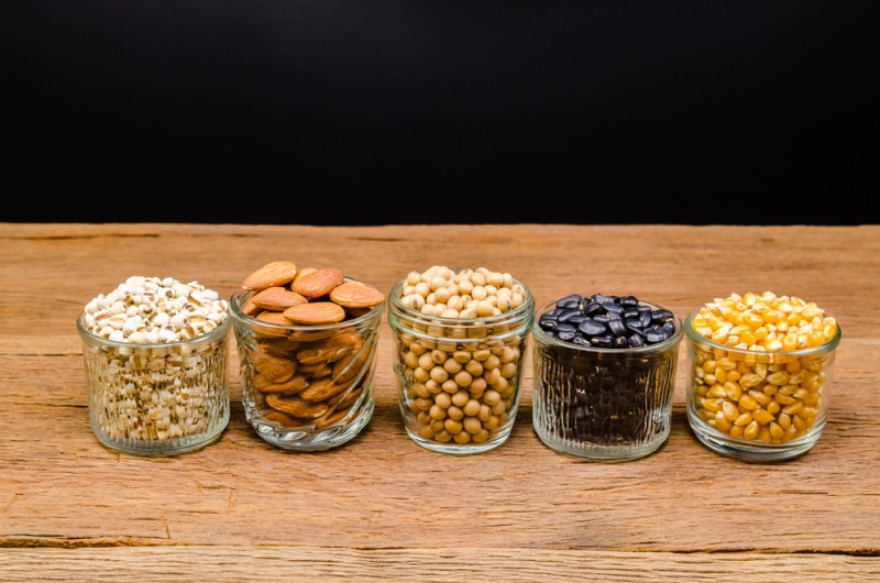 Assorted seeds in small jars on a wooden table