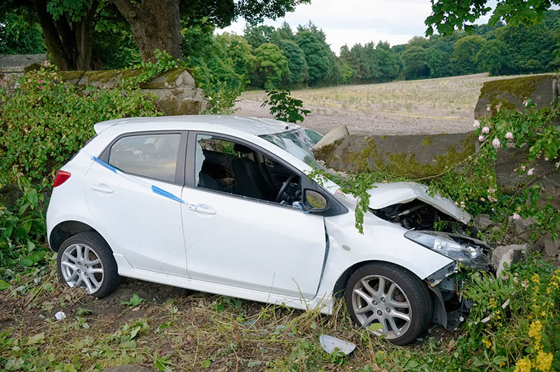 Car crash in rural countryside and damaged wall