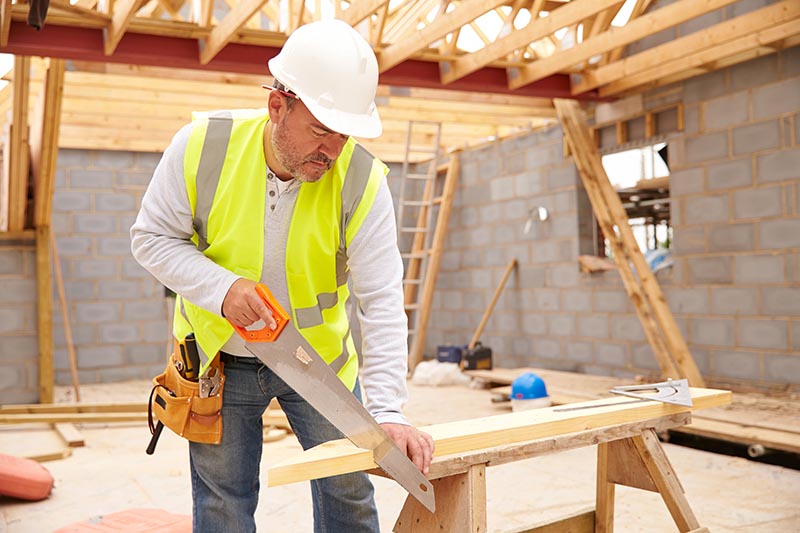 Carpenter Cutting House Roof Supports On Building Site
