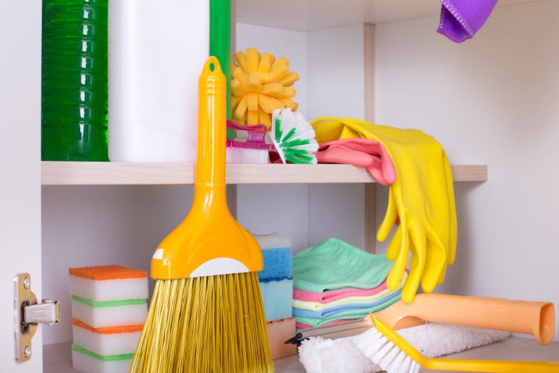 Cleaning supplies and tools arranged on shelves in cabinet storage place