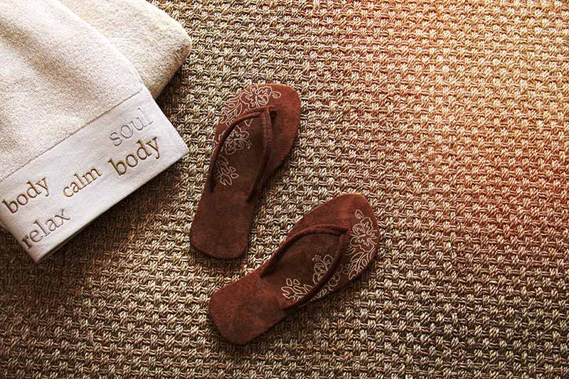 Flip flops with fluffy towels on seagrass rug