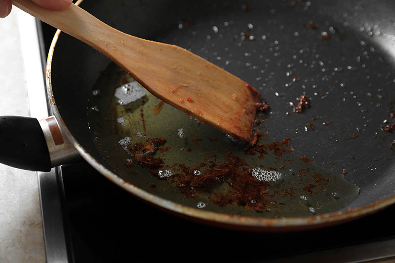 Frying pan with spatula and used cooking oil on stove