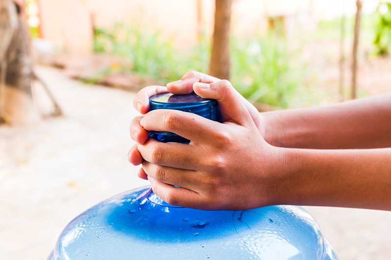 Girl hands with a large mineral water container