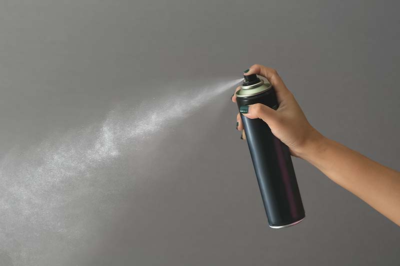 Hand using a can spray
