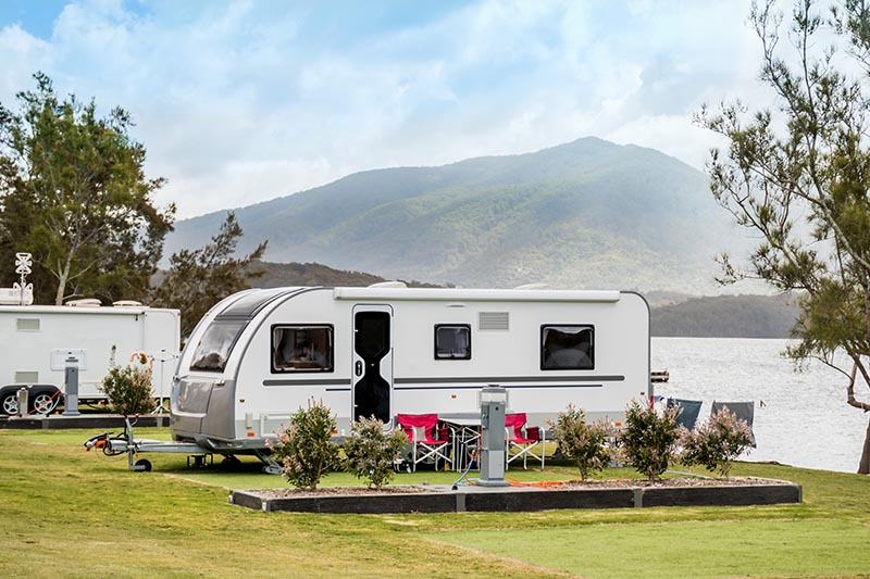 RV caravan camping at the caravan park on a peaceful lake with mountains on the horizon