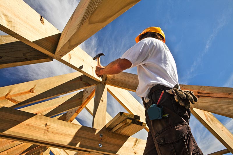Roofer, carpenter working on roof structure on construction site